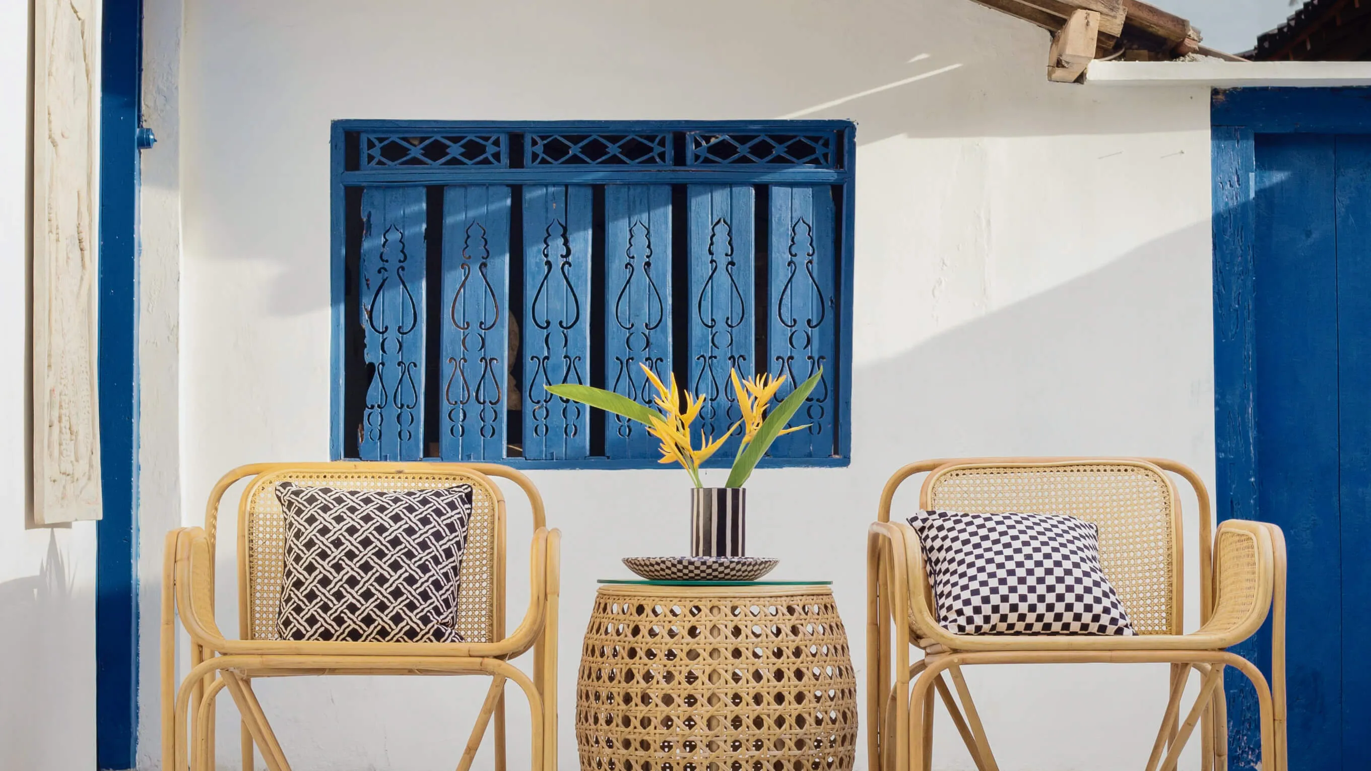 Two patio chairs and a table at a white and blue vacation house